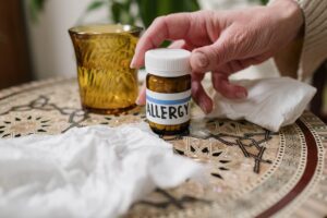 A person holding a tissue and sneezing, with a list of common allergy triggers displayed in the background.
