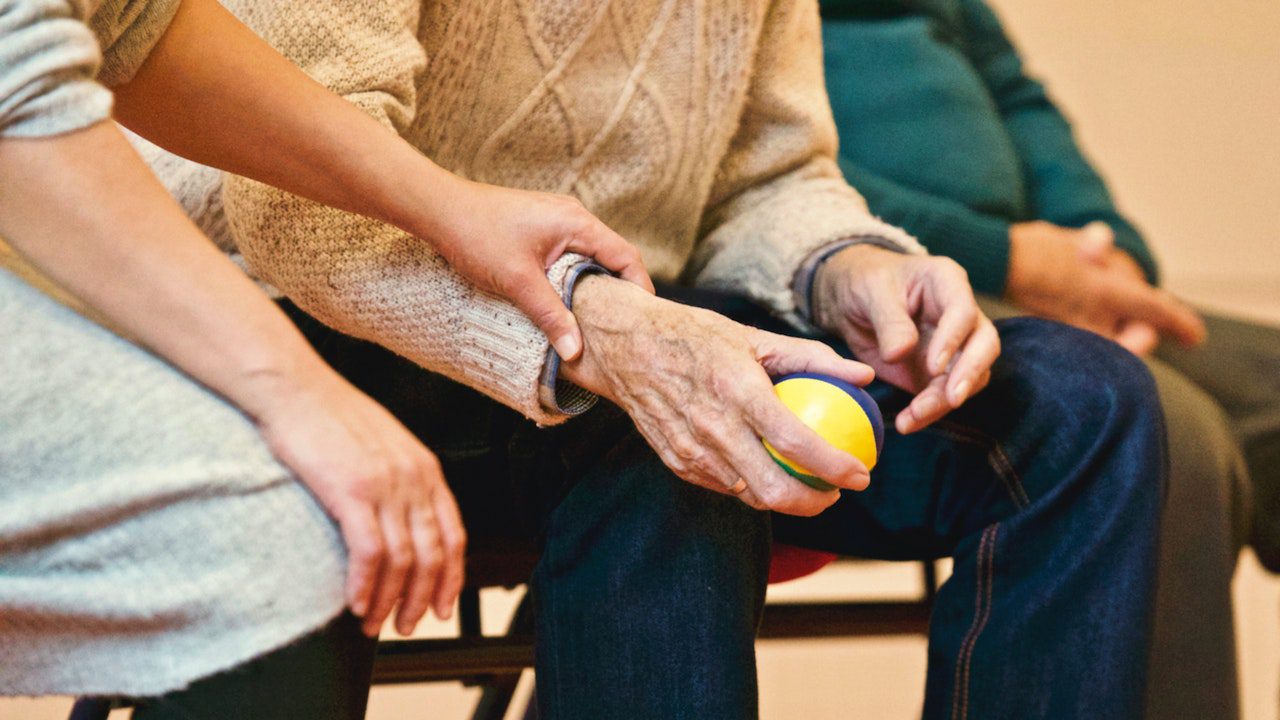 An elderly person holding a walking stick, sitting on a chair with a text overlay that says 'Understanding Arthritis: Types, Symptoms, and Treatment